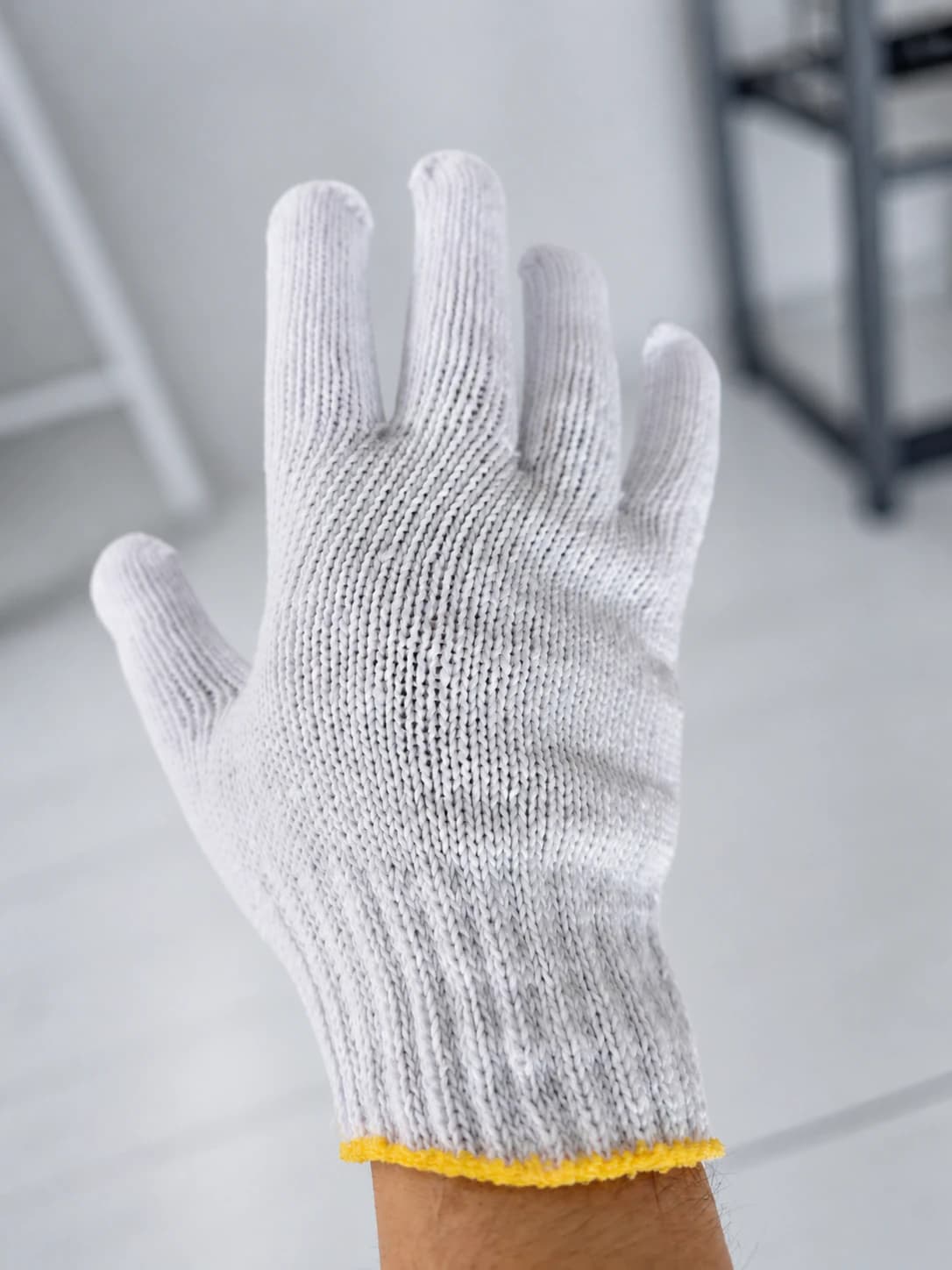 Bleached cotton string glove worn on hand, angled view