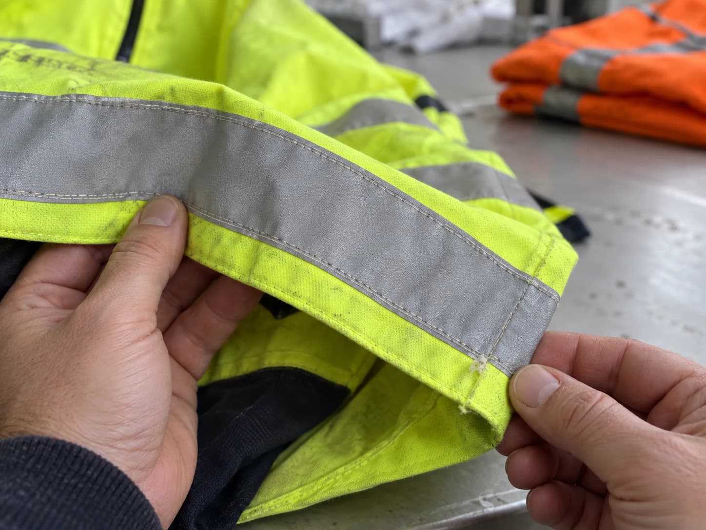 Inspect fabric, reflective bands and seams against the manufacturer's rejection criteria; appearance is not a laboratory reflectivity test.