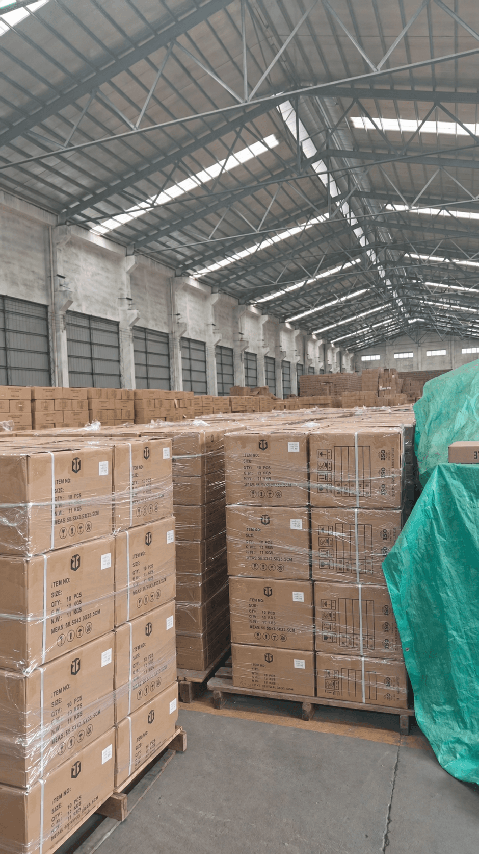 Wrapped cartons stacked on pallets inside a warehouse.