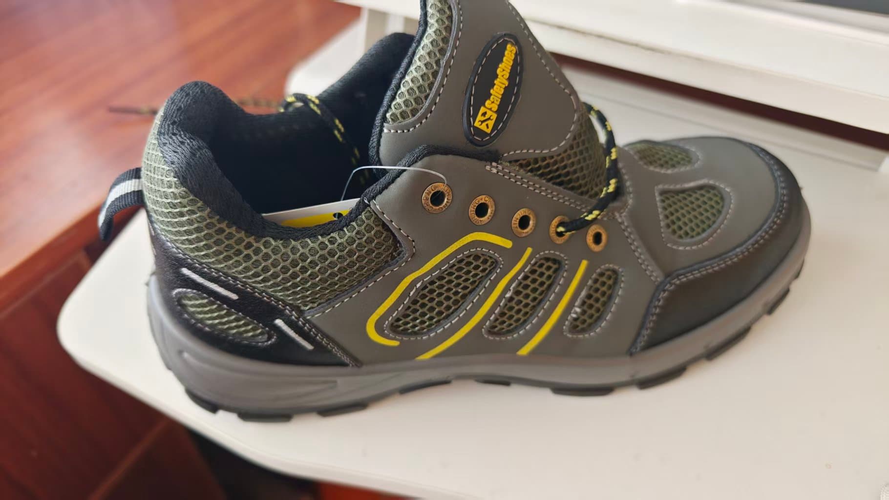 A grey footwear sample with mesh panels and yellow accents.