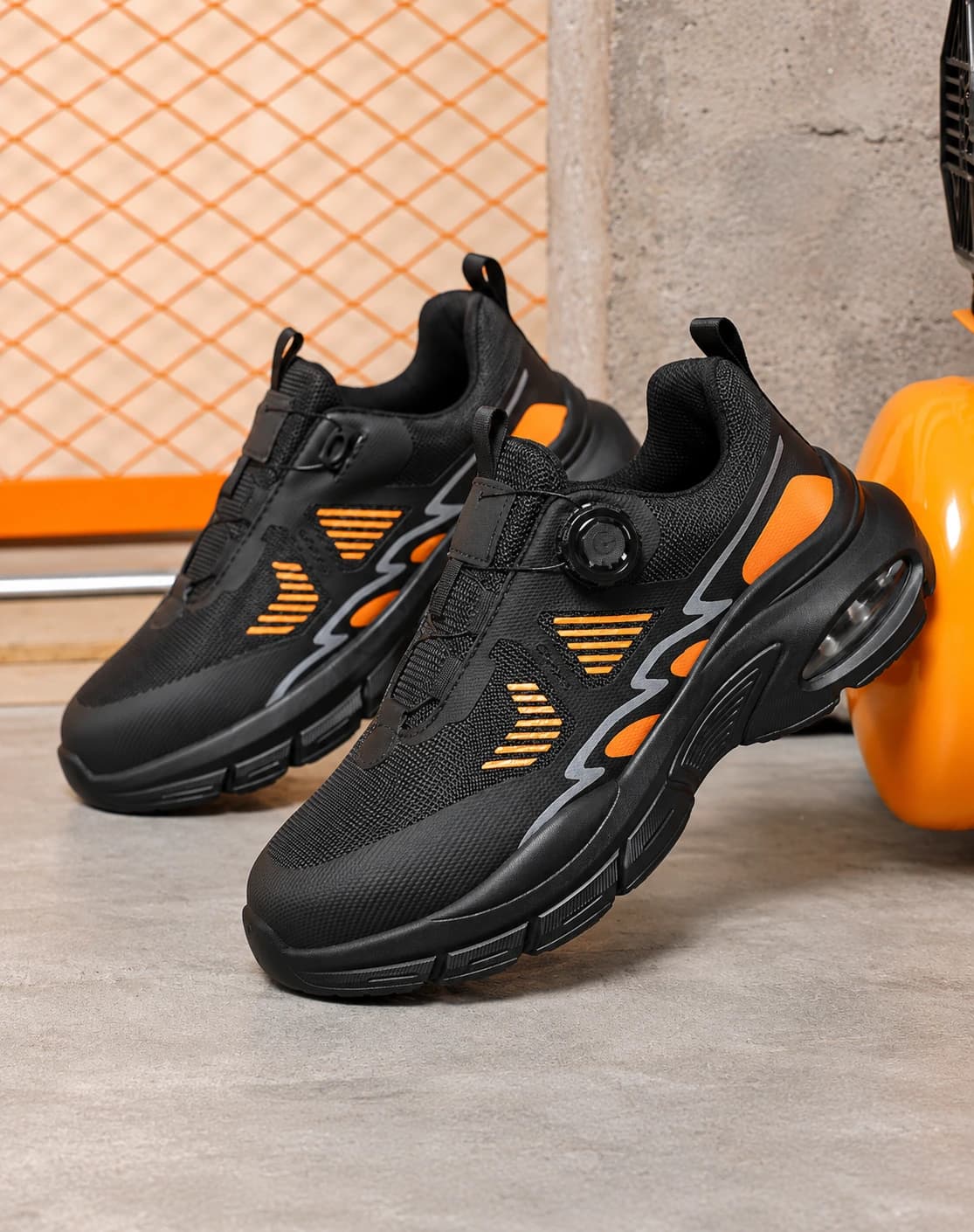 Front view of a pair of black and orange safety shoes